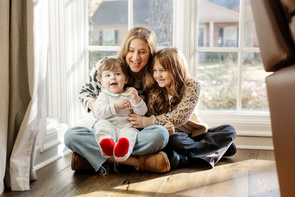 Siblings laughing together in soft natural light during a playful family session in Little Rock