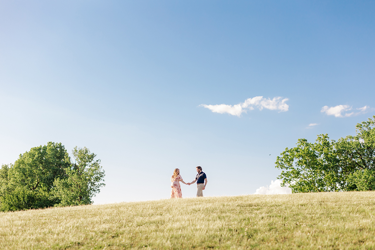 Expecting couple walking along the ridge during golden hour in an Arkansas park.