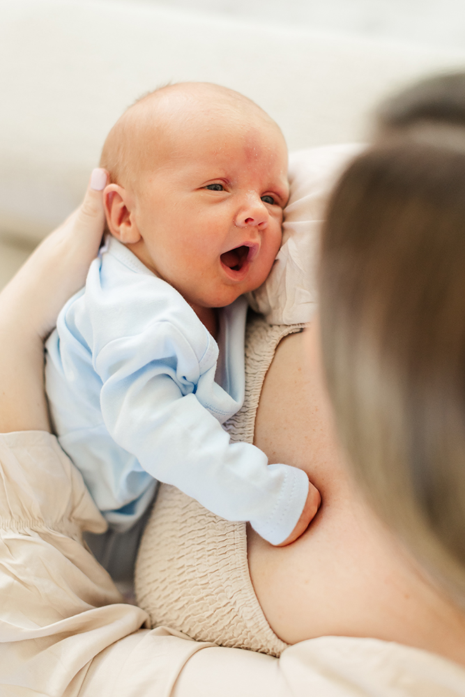 Close-up of newborn yawning during lifestyle family photography session.