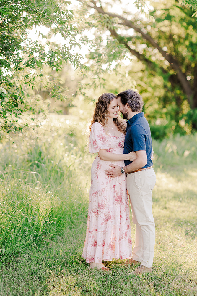 Couple holding hands and laughing during an outdoor maternity session in Arkansas.