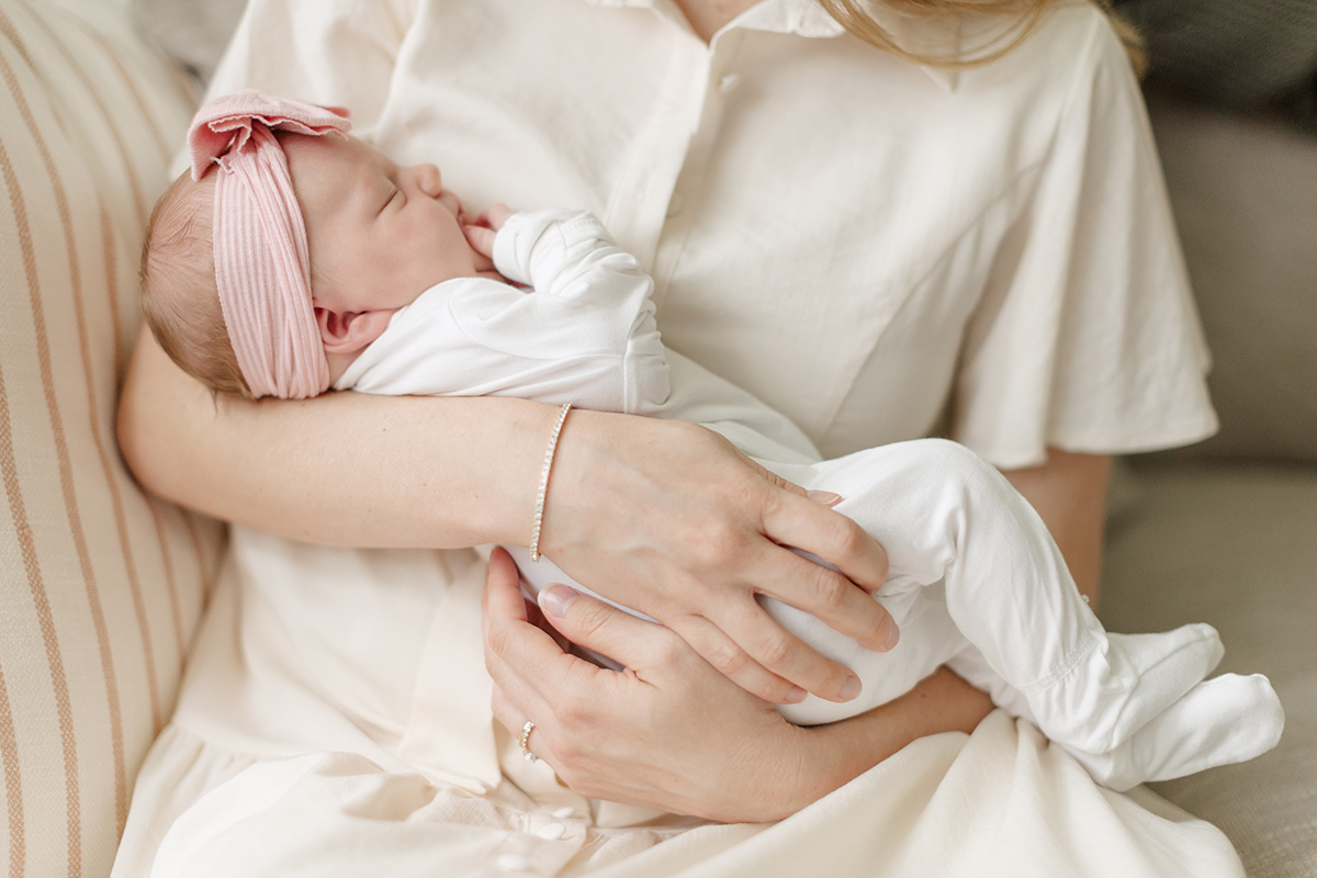 Mother holding newborn in natural light within their home