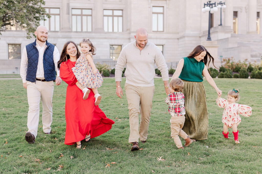 Extended family in colorful coordinated outfits with fall textures during a playful outdoor photo session in Central Arkansas