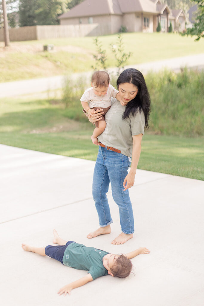 toddler laying down on the driveway during playful family photos