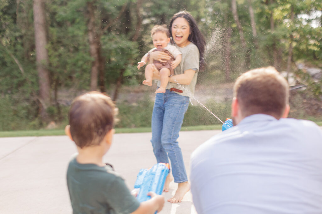father and son having fun during a water gun fight during their playful family photography session