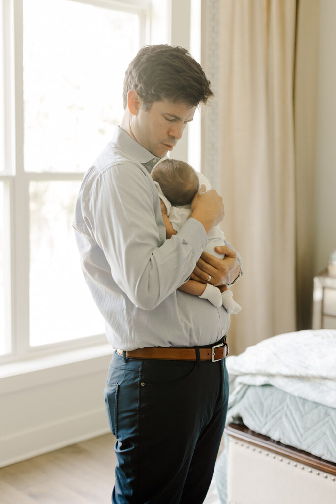 Dad holding newborn during a candid lifestyle family portraits in little rock